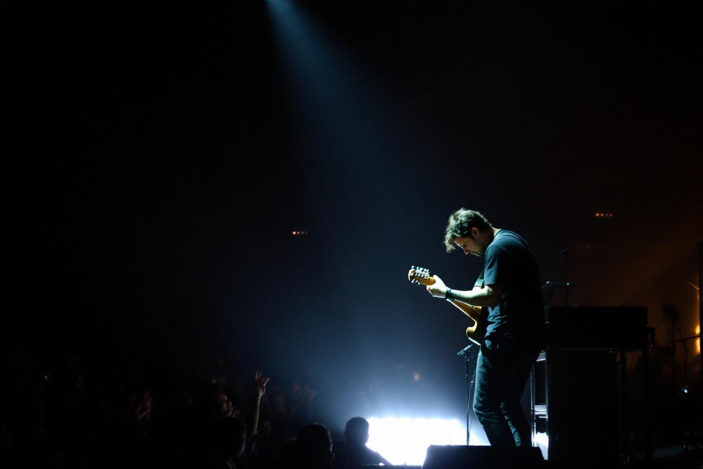 Musicien jouant de la guitare sur scène dans une lumière dramatique