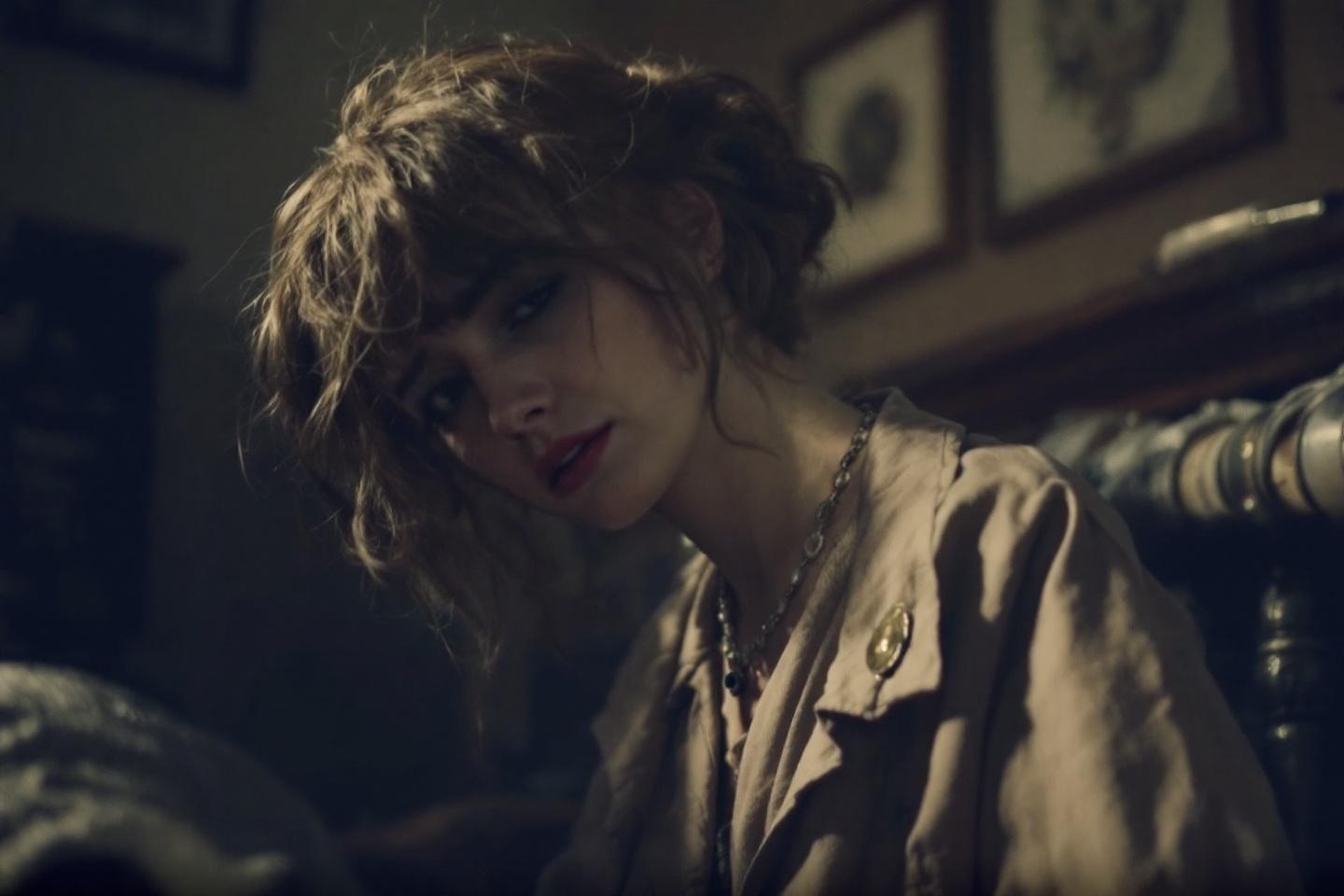 Femme pensive aux cheveux bouclés, lumière tamisée