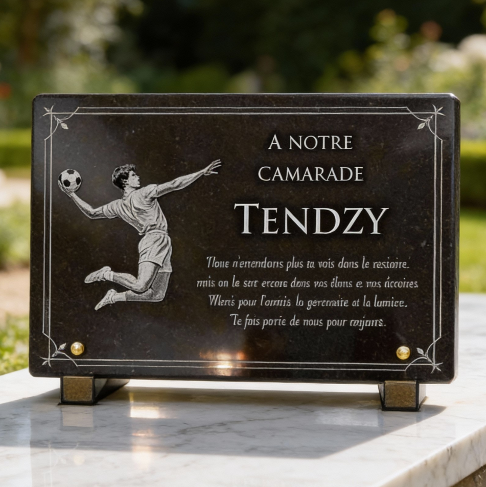 Une plaque commémorative avec une illustration gravée d'un gardien de but de football et une inscription en français dédiée à un ami nommé Tendzy.
