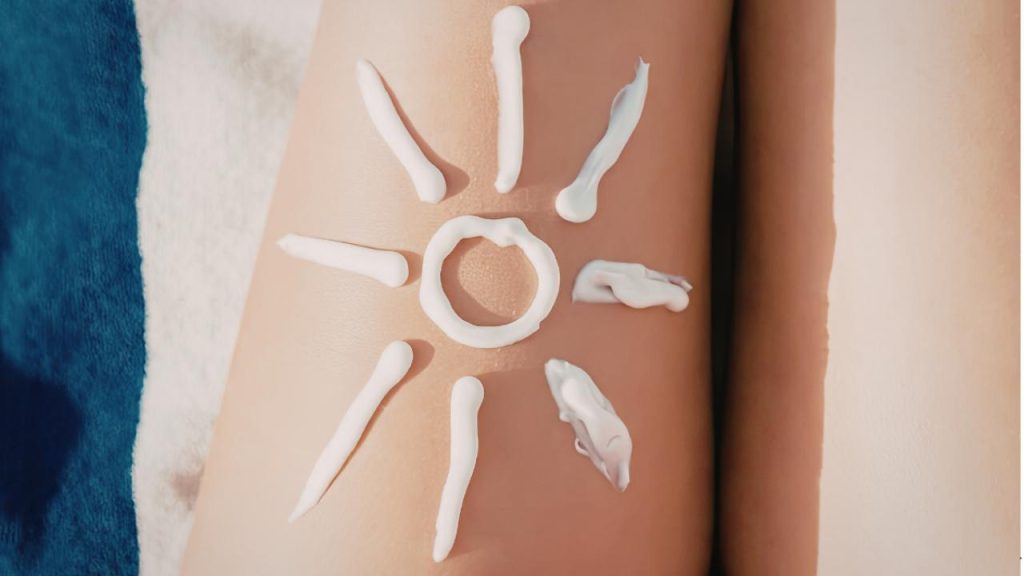 La lotion solaire est appliquée en forme de soleil sur la peau d'une personne, les zones de fond montrant une serviette et la peau nue.